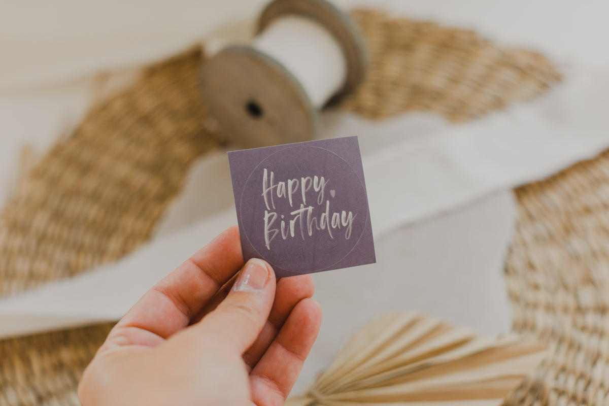 runde lila Aufkleber mit der Aufschrift "Happy Birthday"