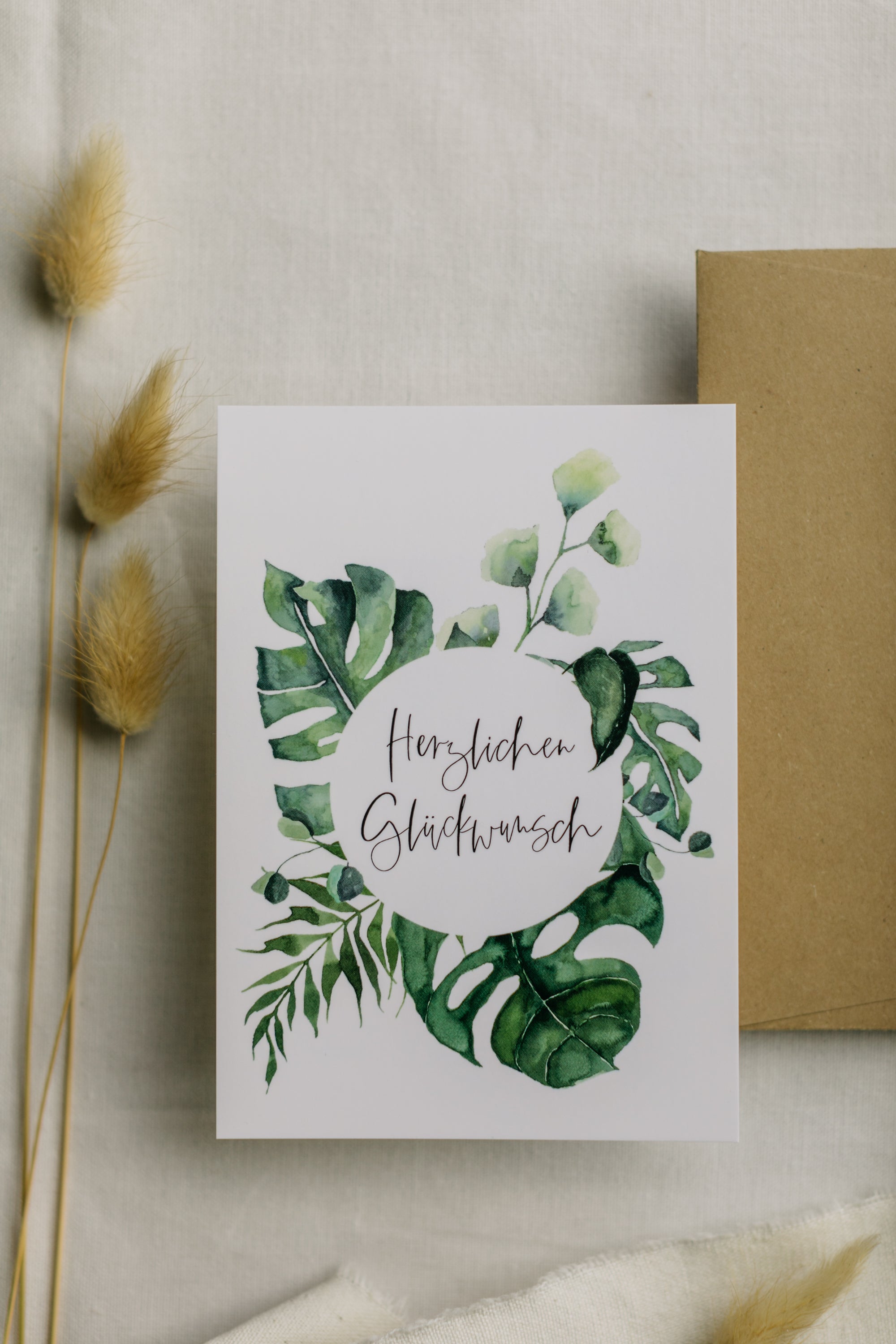 Postkarte grüne Monstera mit dem Aufdruck "Herzlichen Glückwunsch"
