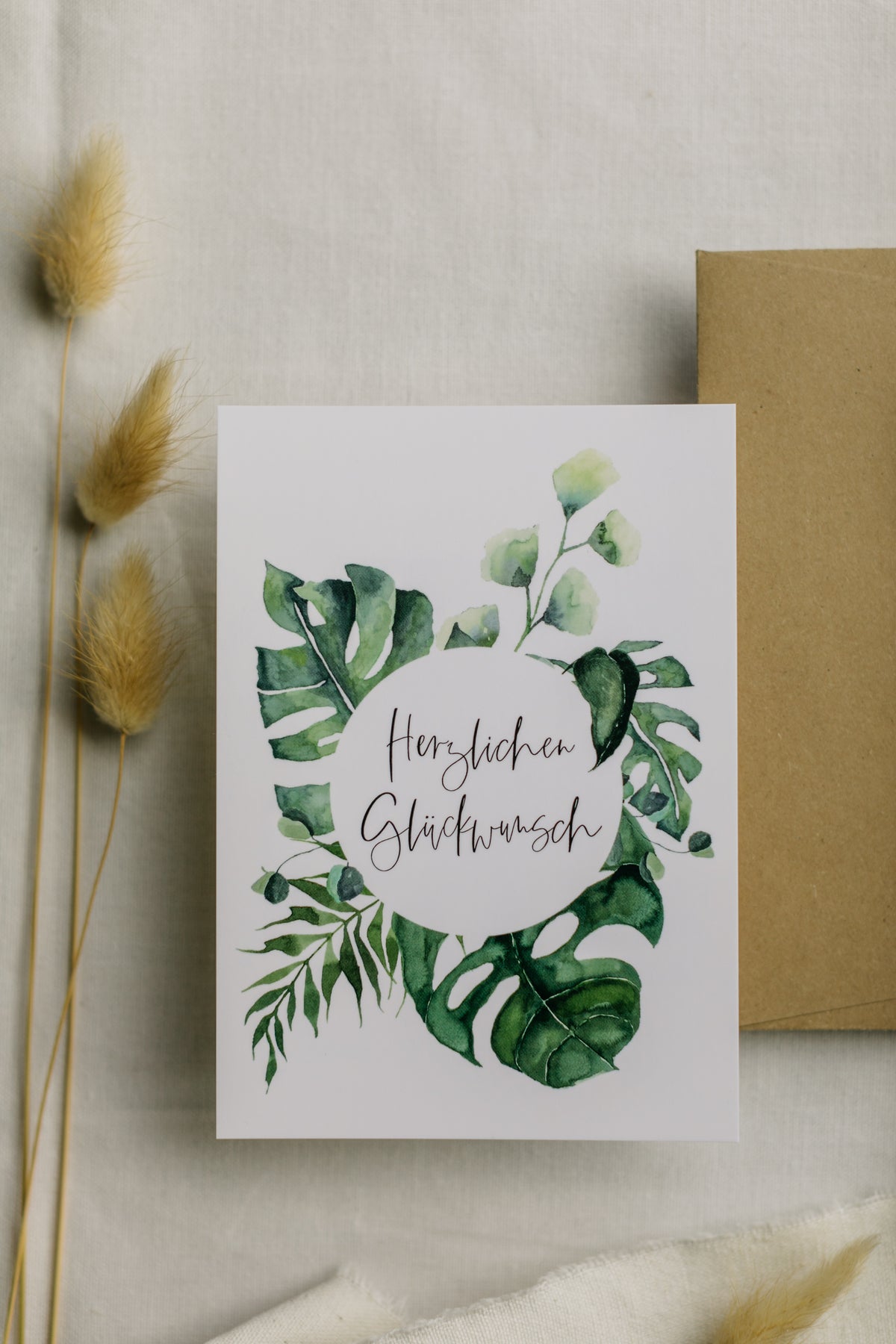 Postkarte grüne Monstera mit dem Aufdruck "Herzlichen Glückwunsch"