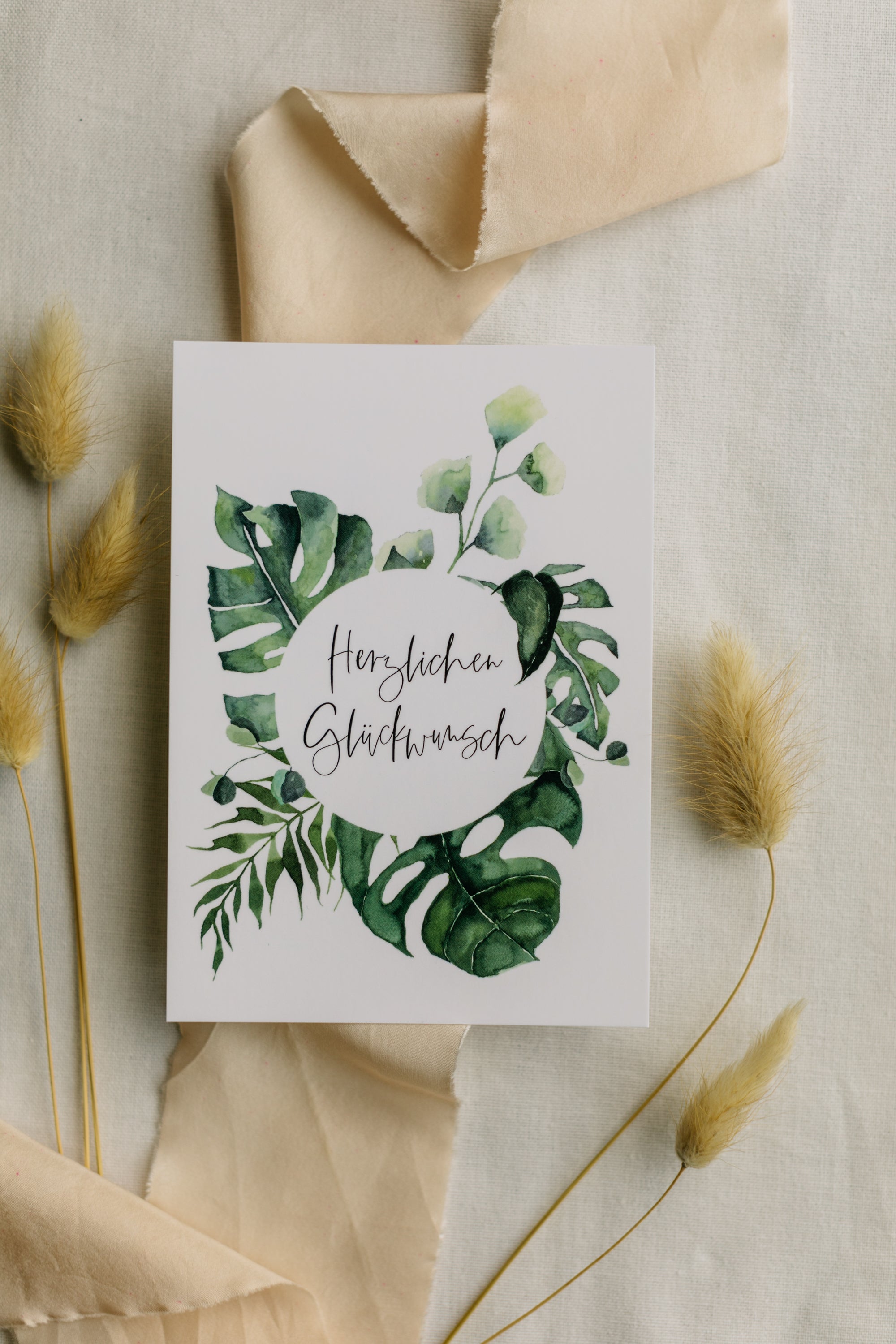 Postkarte grüne Monstera mit dem Aufdruck "Herzlichen Glückwunsch"