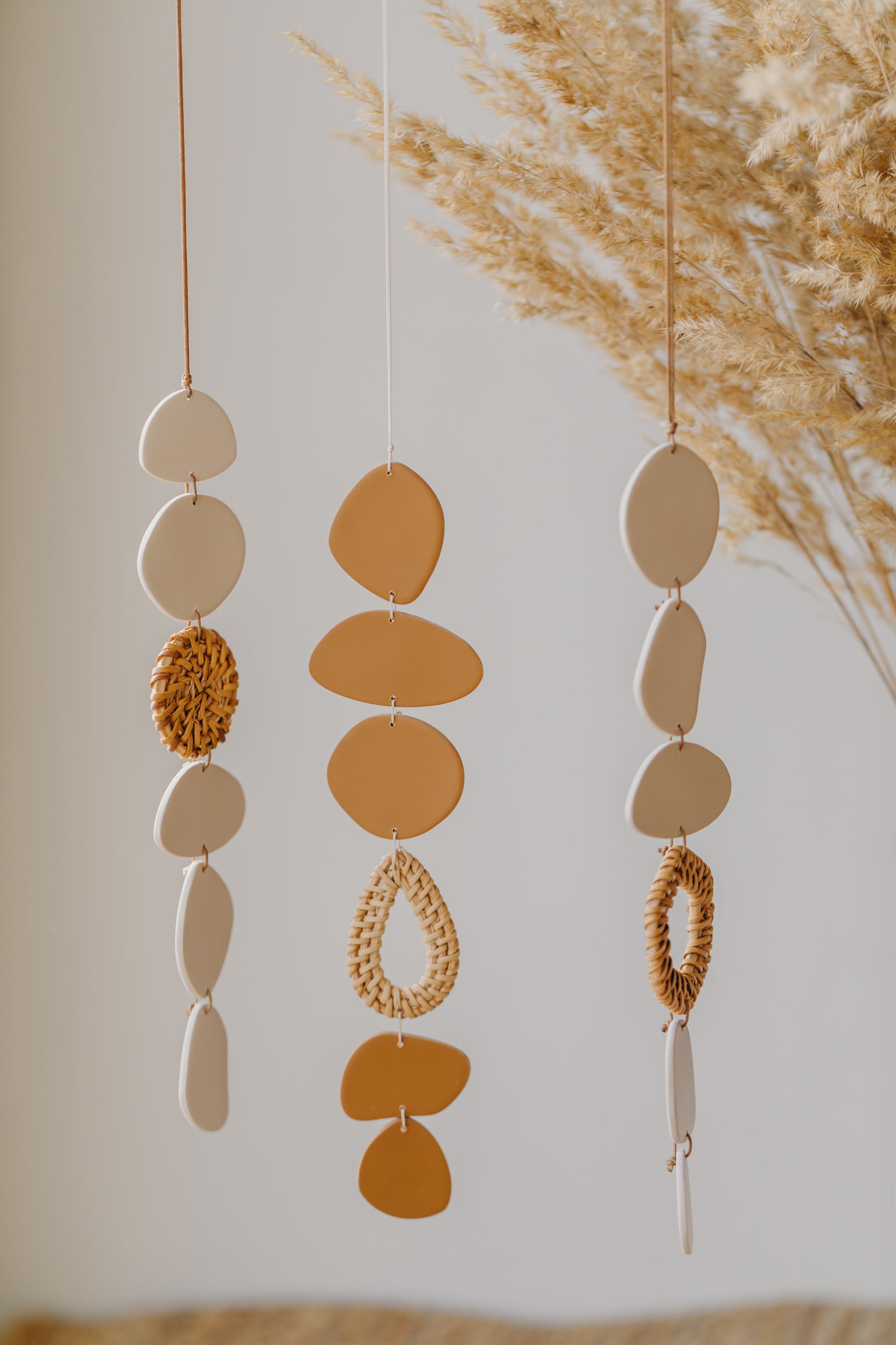 Wall mobile made of polymer clay in natural colors and rattan elements