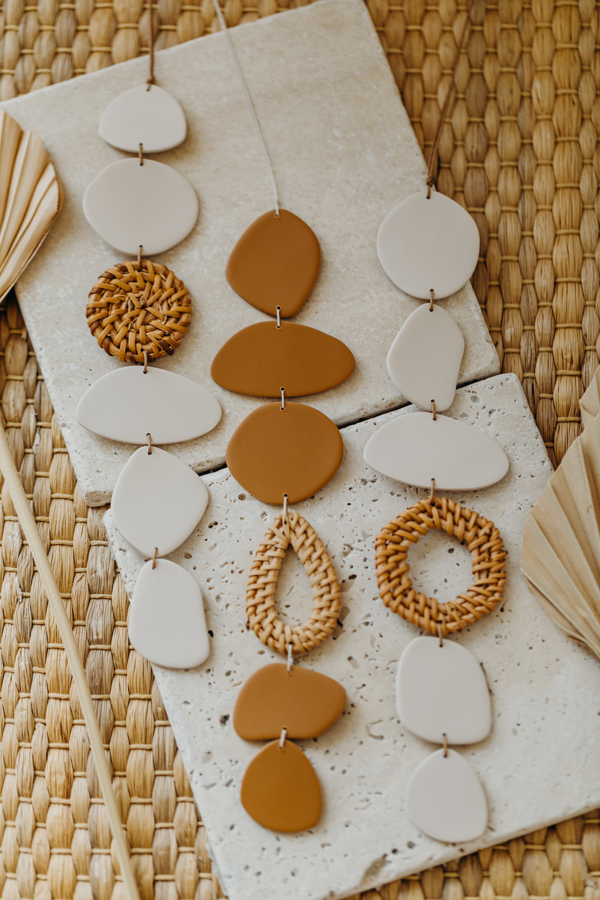 Wall mobile made of polymer clay in cream color with rattan elements