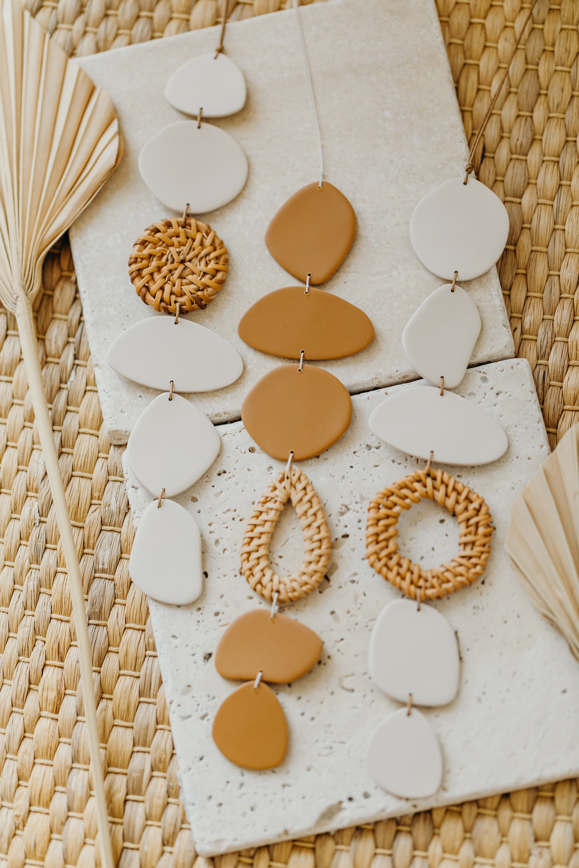 Wall mobile made of polymer clay in cream color with rattan elements