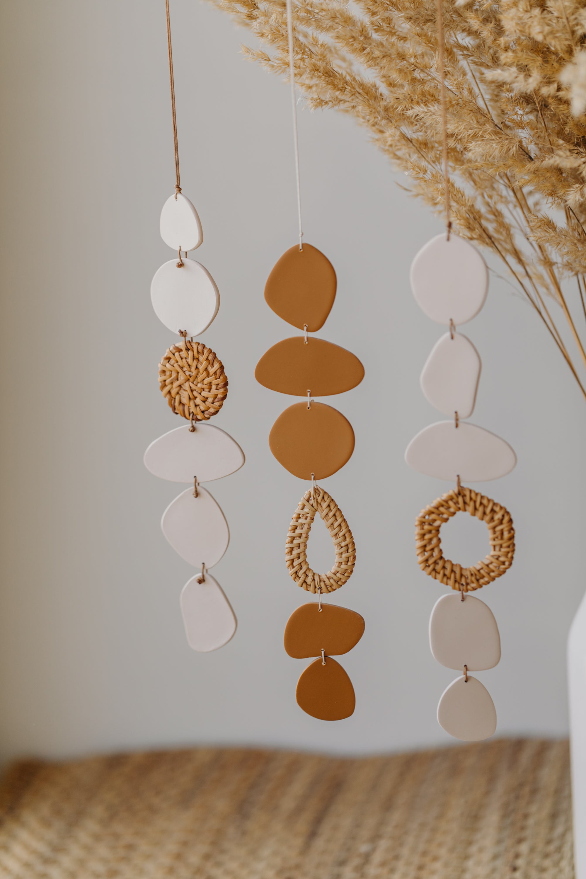 Wall mobile made of polymer clay in cream color with rattan elements