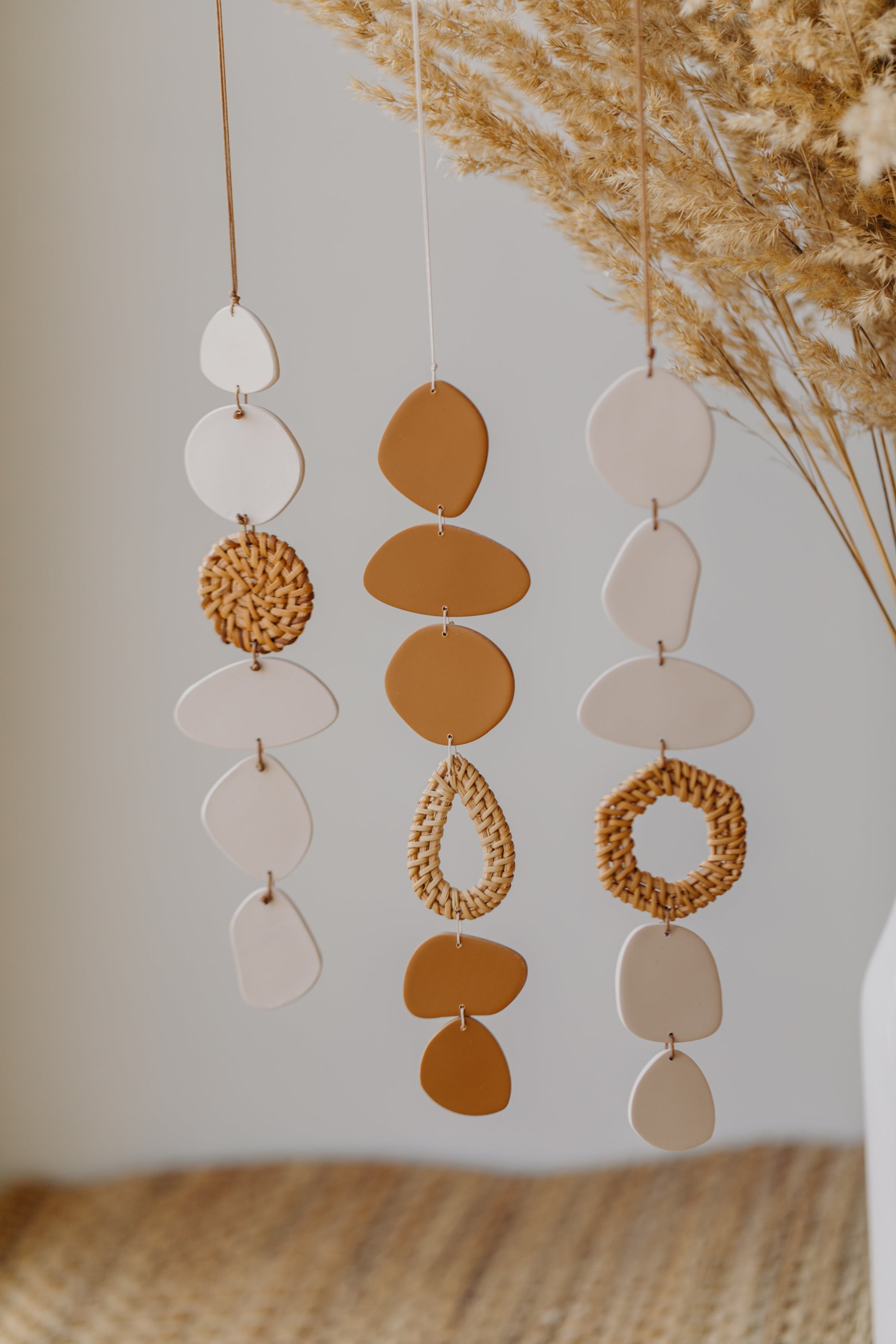 Wall mobile made of polymer clay in cream color with rattan elements
