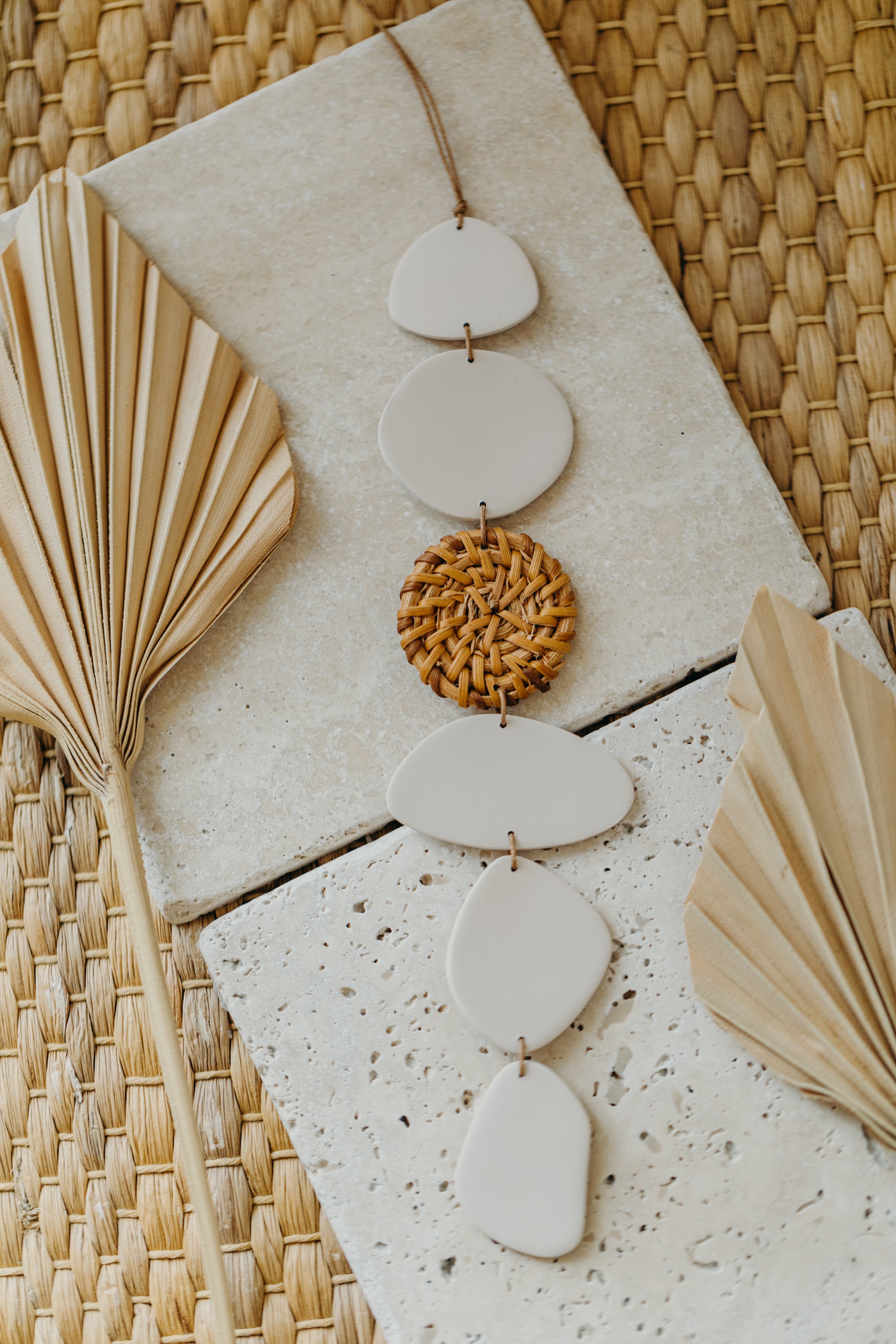 Wall mobile made of polymer clay in cream color with rattan elements