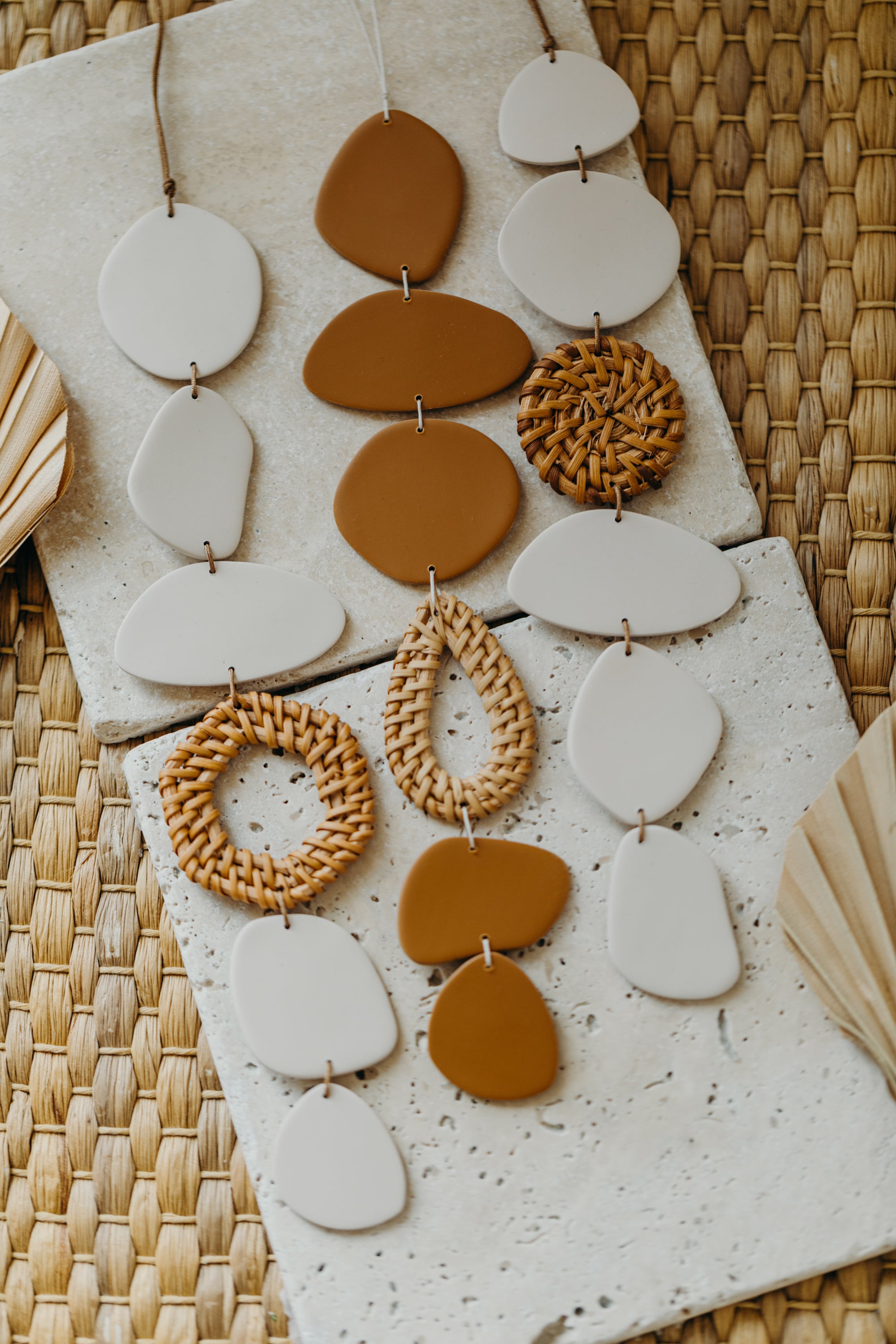 Wall mobile made of polymer clay in cream color with rattan elements