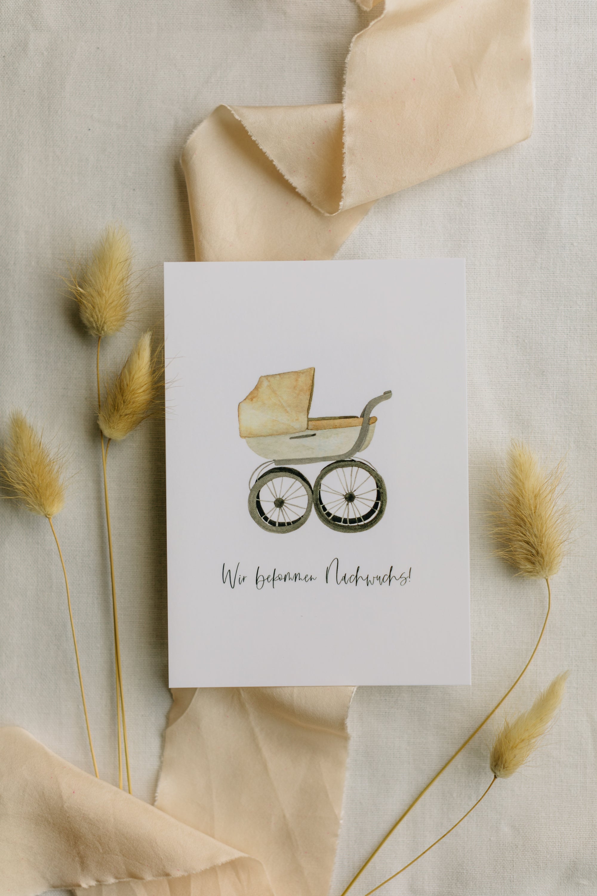 Postkarte Kinderwagen mit dem Aufdruck "Wir bekommen Nachwuchs"