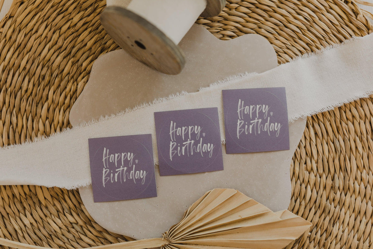 runde lila Aufkleber mit der Aufschrift "Happy Birthday"