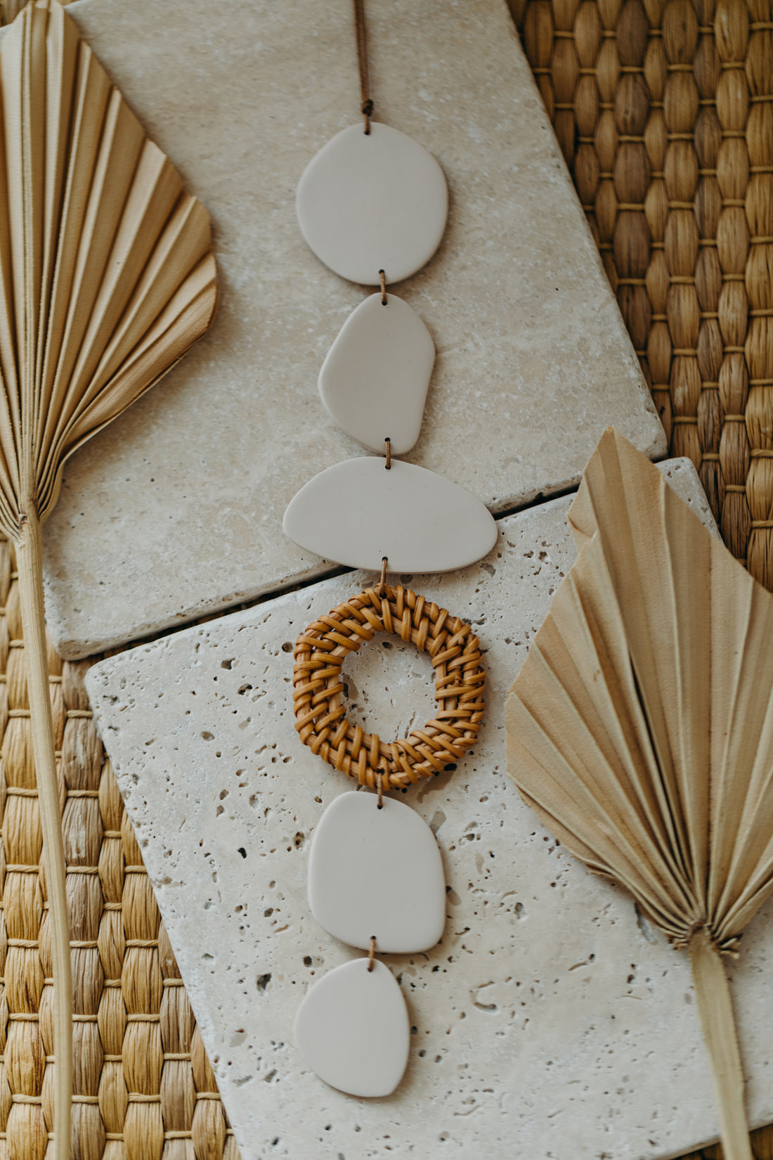 Wall mobile made of polymer clay in cream color with rattan elements