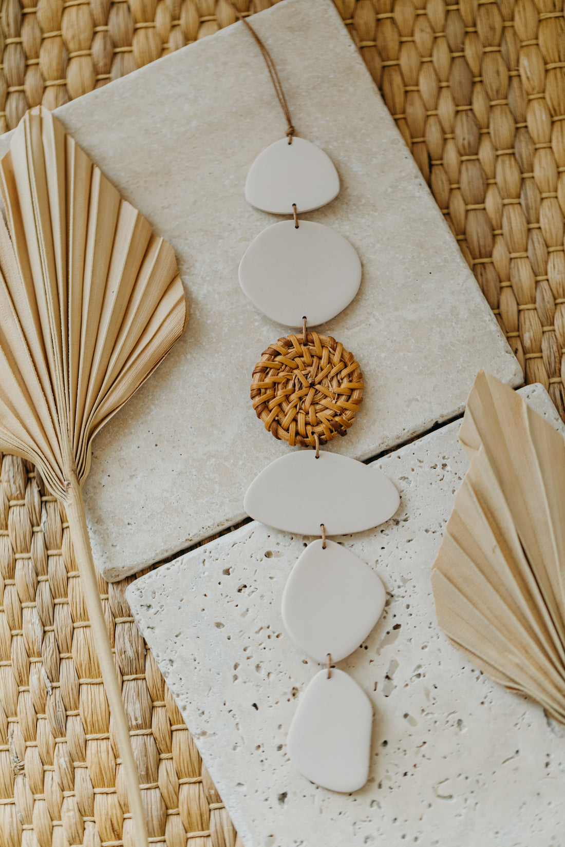 Wall mobile made of polymer clay in cream color with rattan elements